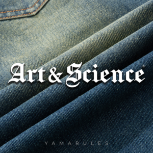 A close-up shot of high-quality denim fabric folds, showcasing layers of deep indigo and vintage wash textures, with "Art & Science" in white Gothic typography centered on the image.